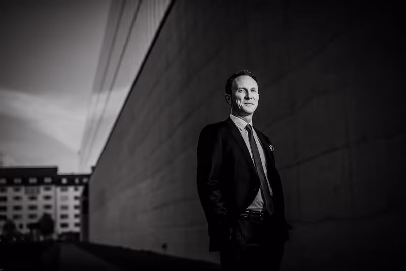 Geschäftsmann in dunklem Anzug und Krawatte, Porträt vor moderner Architektur, Schwarzweiß, professionelle Businessfotografie