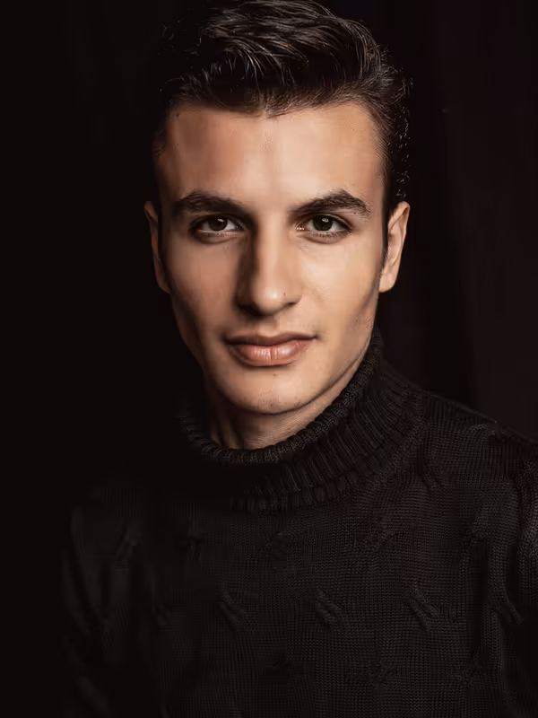 Mann im schwarzen Pullover, Porträt vor dunklem Hintergrund, professionelles Headshot mit direktem Blick
