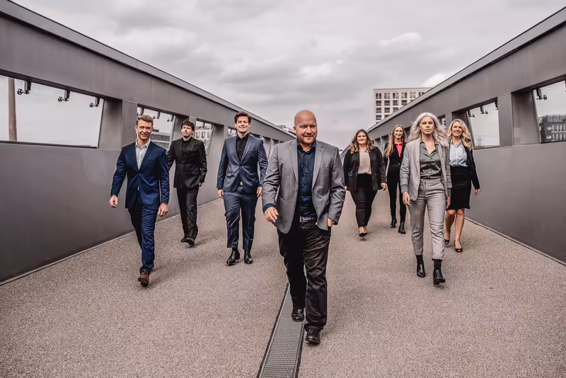 Geschäftsteam läuft durch modernen Tunnel, acht Personen in Business-Kleidung, urbanes Setting, selbstbewusste Atmosphäre
