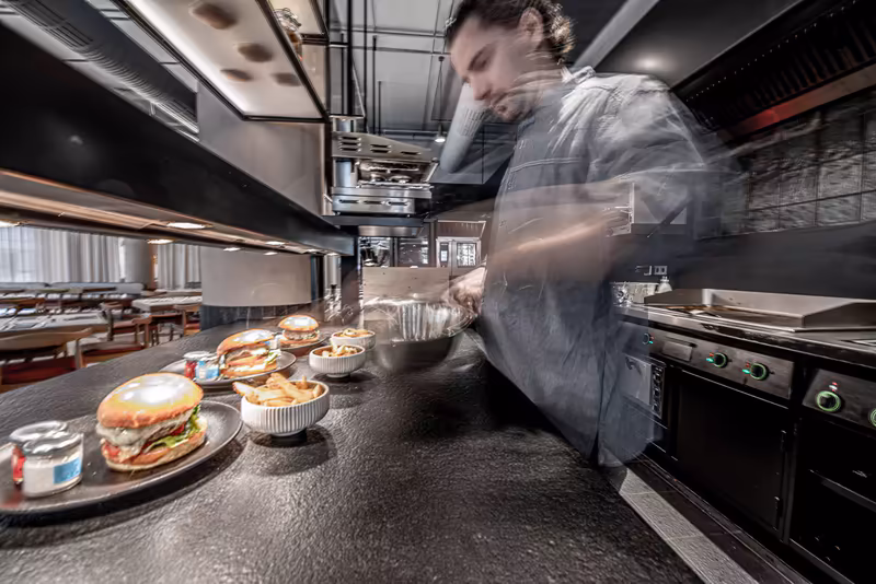 Mann in Businesskleidung arbeitet in moderner Restaurantküche mit Speisen auf Theke