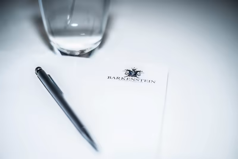 Geschäftliche Stilleben mit Kugelschreiber, Wasserglas und Briefkopf mit Logo auf weißem Untergrund