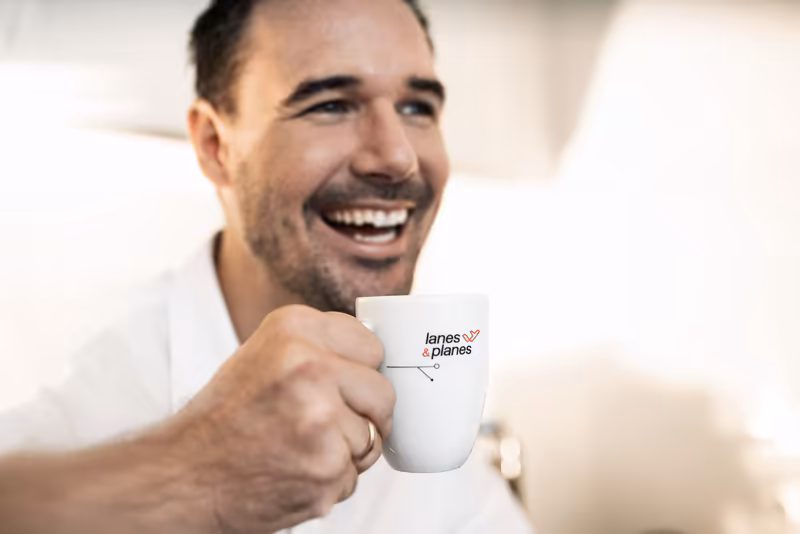 Geschäftsmann mit Tasse lächelt in Kamera, helles Büro-Ambiente, Business-Porträt