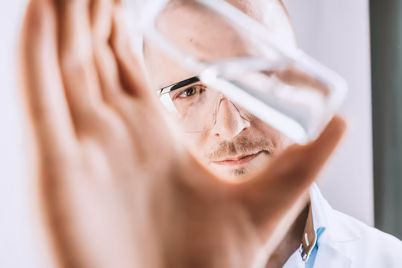 Mann mit Brille und weißem Hemd hält Hand vor Gesicht, konzentrierter Blick, Business-Portrait