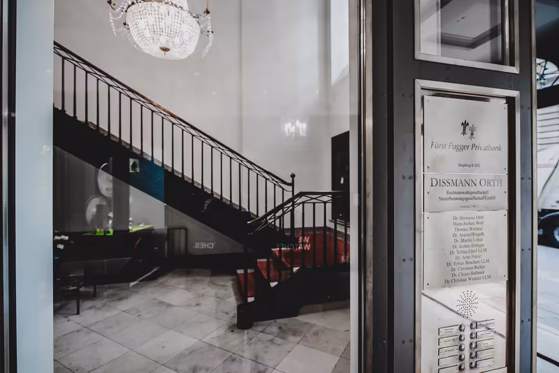 Eleganter Businessgebäude-Eingang mit Treppe, Kristalleuchter und Klingelschild, modernes Interieur in Grau und Schwarz