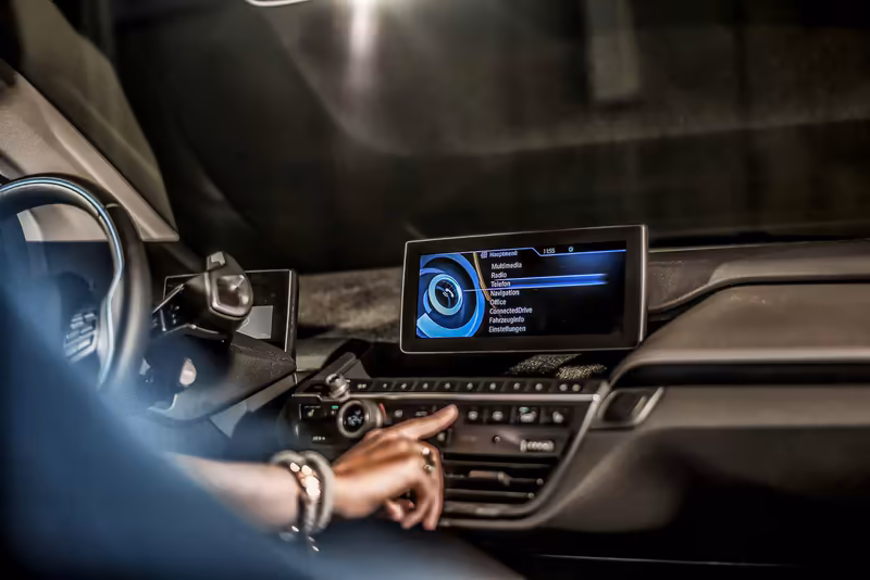 Person bedient Touchscreen-Display im Fahrzeuginneren, modernes Infotainment-System mit blauer Benutzeroberfläche