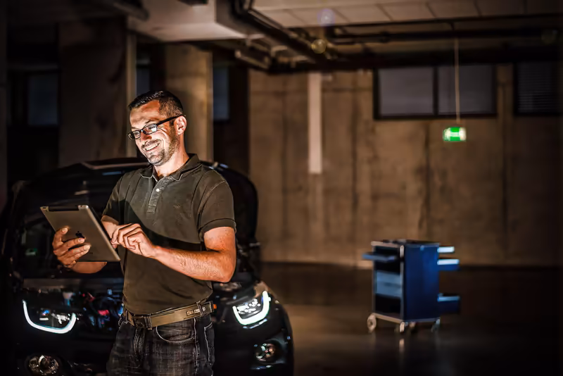 Handwerker mit Tablet in Werkstatt vor Motorrad, professionelle Arbeitsatmosphäre