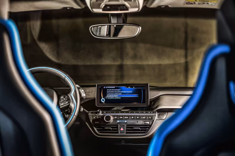 Modernes Elektrofahrzeug-Cockpit mit blauem Lenkrad, digitales Infotainment-Display und technologisches Interieur