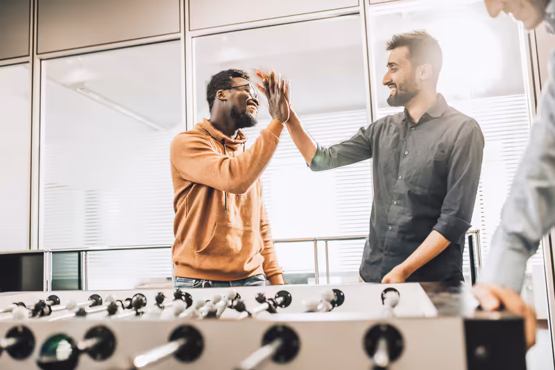Zwei Geschäftsmänner geben sich High-Five in modernem Büro, erfolgreiche Teamarbeit und positive Geschäftsatmosphäre