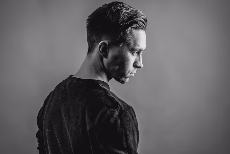 Mann im Profil, dunkles Hemd, nachdenklicher Blick, Studio-Porträt in Schwarzweiß