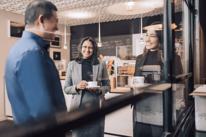 Geschäftsleute unterhalten sich beim Kaffee in modernem Café, entspannte Geschäftsatmosphäre