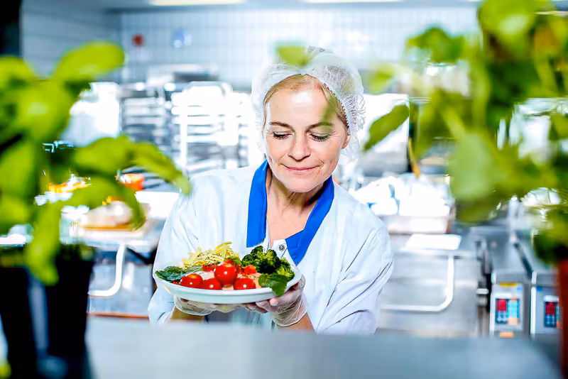 Frau in Laborkleidung präsentiert Salatteller in moderner Küche, Konzept Ernährungswissenschaft