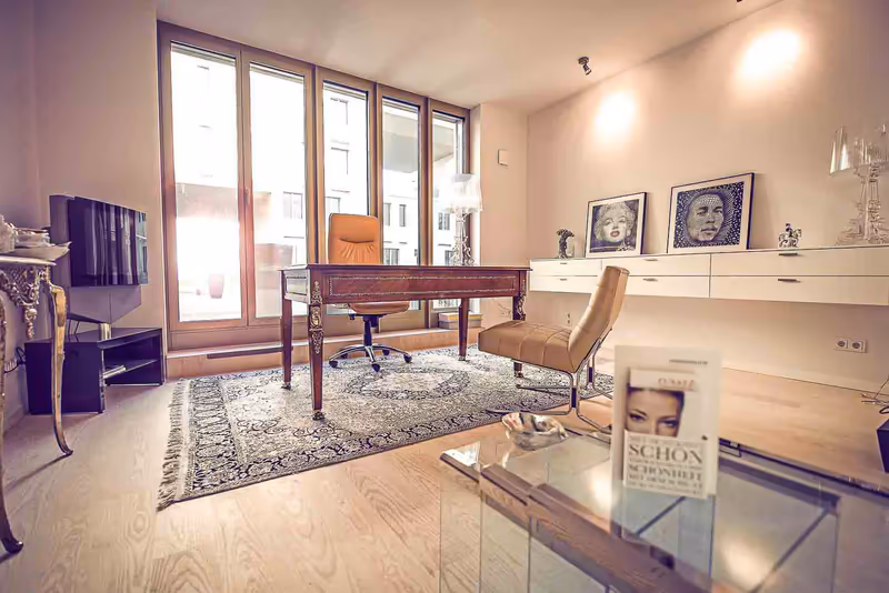 Modernes Buero mit Schreibtisch, Stuehlen und grossem Fenster, elegante Einrichtung mit Kunstwerken an der Wand