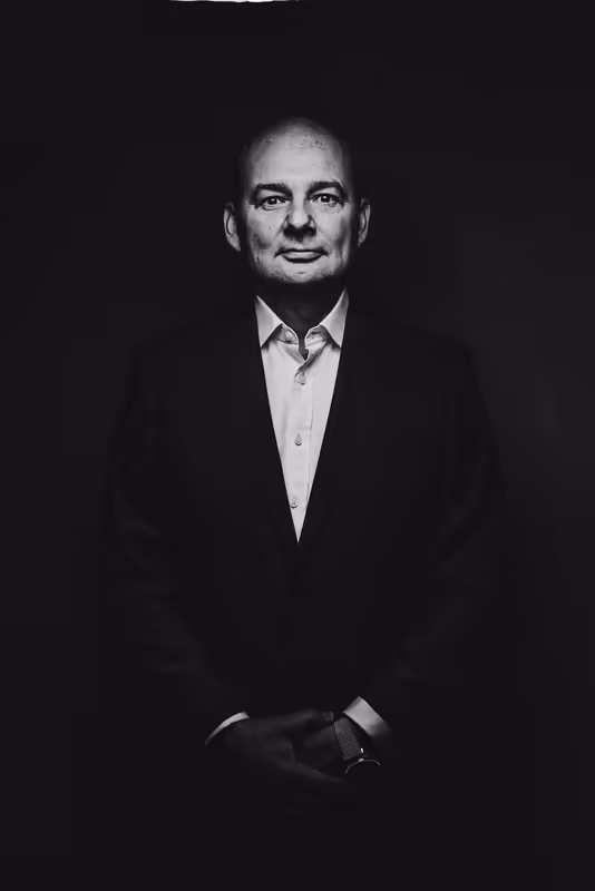 Mann im dunklen Anzug und weißem Hemd, Porträt vor schwarzem Hintergrund, ernster Blick, Business-Portrait