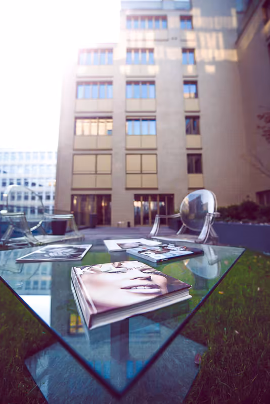 Moderne Bürogebäude mit Glastisch, Designmagazinen und Metallskulptur auf Innenhof-Terrasse