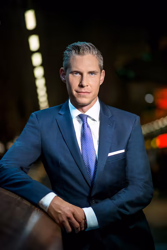 Mann im dunkelblauen Anzug mit Krawatte, Porträt bei Nacht mit urbaner Beleuchtung, professionelle Business-Fotografie