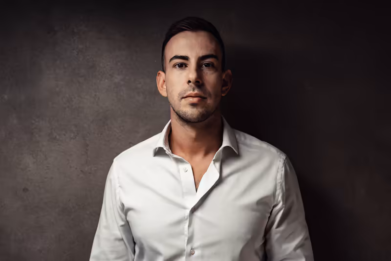 Mann in weißem Hemd vor grauem Hintergrund, professionelles Portrait mit seriösem Blick