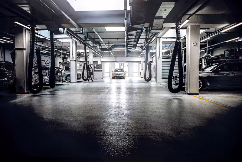 Moderne Tiefgarage mit Zapfsäulen, Parkplätzen und Auto in symmetrischer Perspektive, professionelle Industriefotografie