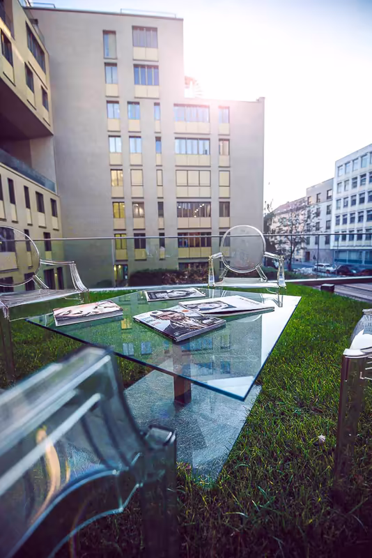 Moderner Innenhofbereich mit Glastischen, Grünfläche und Architekturgebäuden, professionelle Geschäftsumgebung