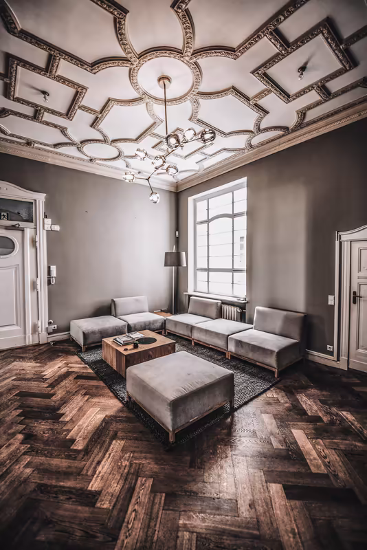 Elegantes Business-Lounge-Interieur mit Designerdecke, modernem Sofa und Holzparkett in klassischem Büroraum