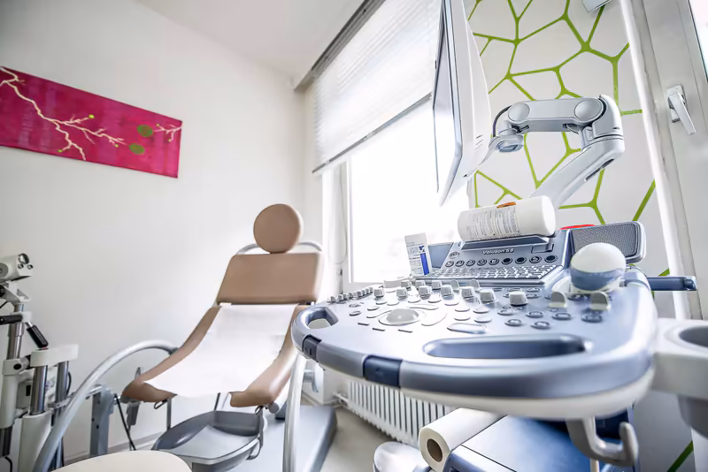 Medizinisches Ultraschallgerät in moderner Praxis mit Behandlungsliege am Fenster
