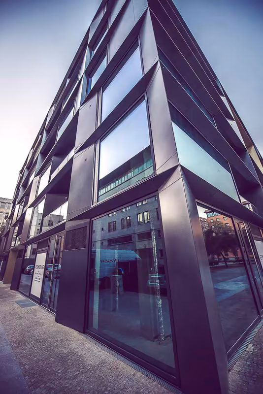 Modernes Geschäftsgebäude mit Glasfassade und lila Metallrahmen, Froschperspektive gegen Himmel