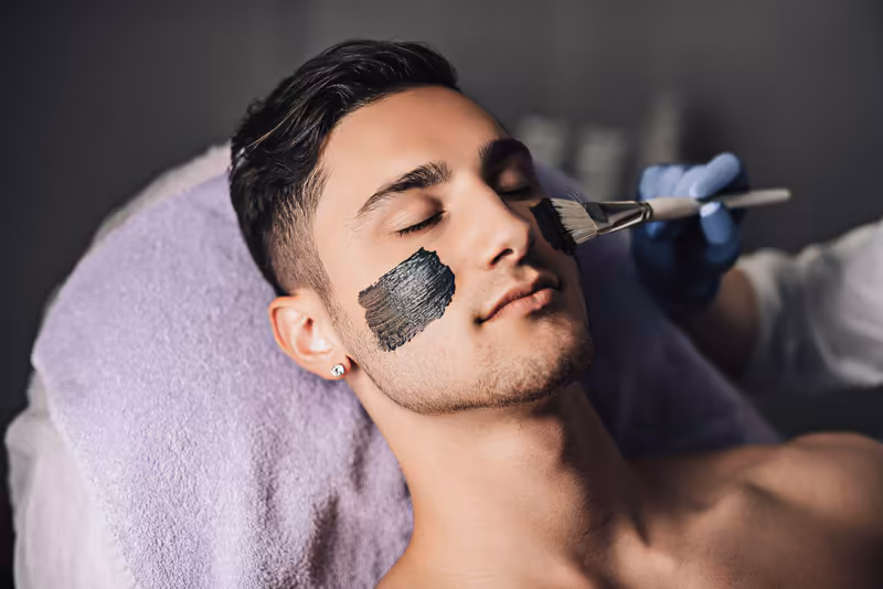 Mann erhält professionelle Gesichtsbehandlung mit Pinsel, entspannte Atmosphäre, Beauty und Wellness Service