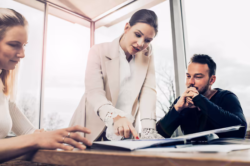 Geschäftsteam in modernem Büro bespricht Dokumente am Tisch, konzentrierte Arbeitsatmosphäre