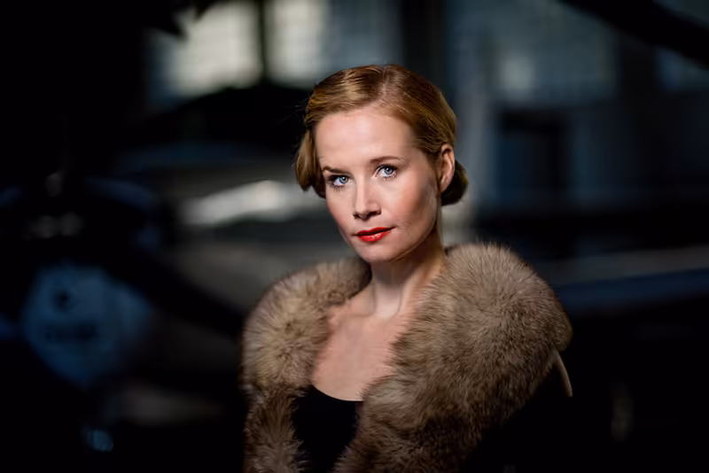 Porträt einer Frau mit rötlichem Haar und rotem Lippenstift, Pelzstola, eleganter Blick in klassischem Studio-Setting